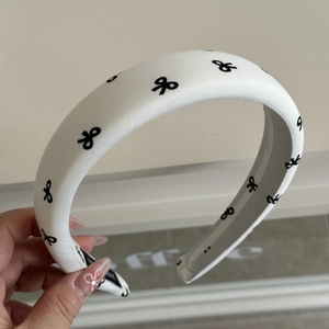Détail du serre-tête rembourré blanc avec imprimé nœuds noirs et étiquette