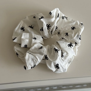 Détail d'un chouchou blanc avec motif de nœuds noirs et texture en coton plissé
