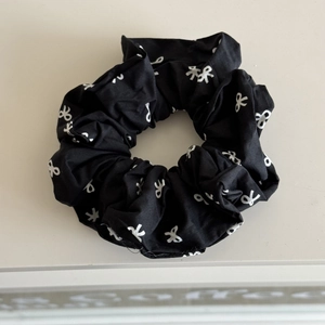 Détail d'un chouchou en coton noir avec imprimé nœud blanc et texture du tissu