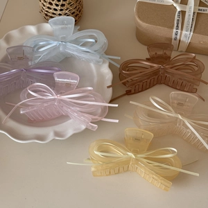 Matte ribbon bow claw clips in pastel macaron colors displayed on a white plate