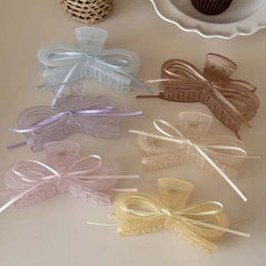Close-up of ballet style ribbon bow hair claws in six pastel colors on a desktop
