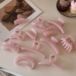 Pink jelly glitter hair claws in various elegant shapes displayed on a minimalist desk