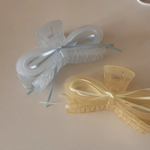 Detail of large translucent resin hair claws with delicate ribbon bows in blue and yellow