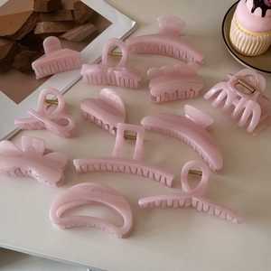 Flat lay detail of pastel pink jelly hair claw clips with glitter in various shapes