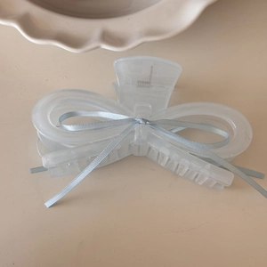 Detail of light blue ribbon bow hair claw with matte texture and sturdy comb teeth
