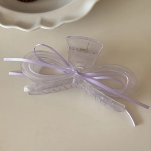 Close-up of light purple bow hair claw clip with satin ribbons and visible metal spring