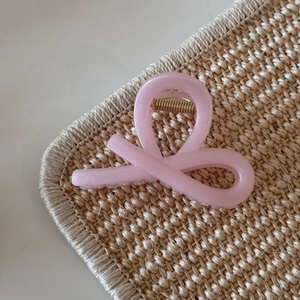 Close-up of pink jelly glitter hair claw clip with a sleek bow design on woven texture
