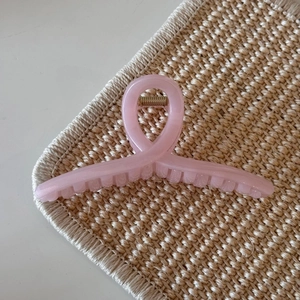 Close-up of translucent pink jelly hair claw clip with subtle glitter on beige mat