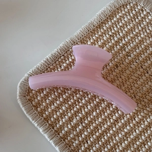 Close-up of translucent pink jelly hair claw clip with fine glitter on woven mat