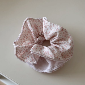 Detail van roze bloemenpatroon en zachte geplooide textuur op de katoenen haarscrunchie