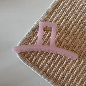 Macro detail of a large pink jelly hair claw clip with shimmer finish and gold metal spring