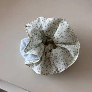 Detail van bloemen scrunchie met blauwe patronen en lichtblauwe textuur stof