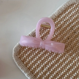 Close-up of translucent pink bow hair claw clip with fine glitter and golden spring