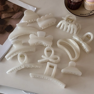 Flat lay of cream resin hair claws with pearlescent finish and gold metal springs