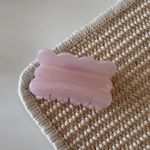 Close-up of pink jelly glitter hair claw clip with a sleek wavy design and resin texture