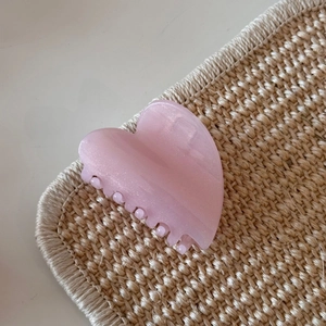 Close-up of heart-shaped hair claw with pink glitter finish on a woven mat