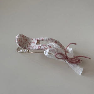 Detail van bloemen haarklem met roze katoenen stof en witte kanten randafwerking