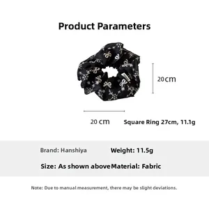Detail view of 20cm black scrunchie with white bow and snowflake prints on soft fabric