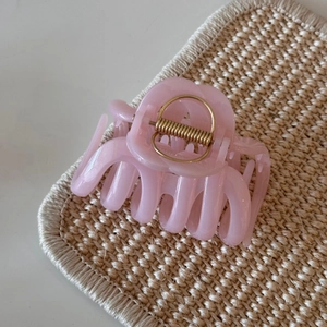 Detail view of pink jelly hair claw clip with subtle glitter on a woven background