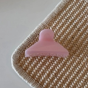 Detail view of pink jelly hair claw clip with frosted texture on woven mat surface