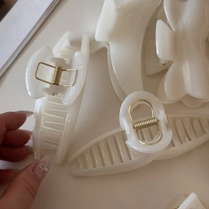 Detail of cream white jelly hair claws showing smooth resin texture and gold metal spring
