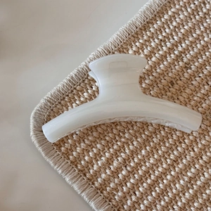 Detailed close-up of pearl white resin hair claw clip with glossy finish and sturdy teeth