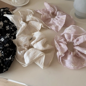 Detail of oversized organza scrunchies with floral embroidery and bow patterns