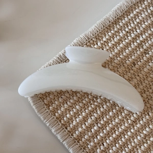 Detail of elegant cream white crescent hair claw clip on minimalist straw background