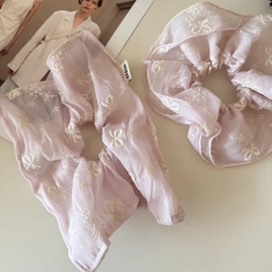 Detail view of two light lavender organza scrunchies with white floral embroidery