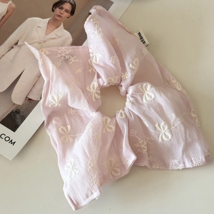 Detail of pink chiffon oversized scrunchie with white bow and flower embroidery