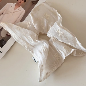 Detail of white translucent scrunchie with wave texture and delicate bow embroidery