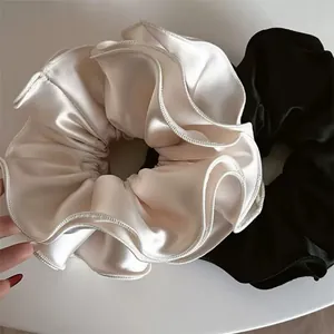 Dettaglio di elastici per capelli in raso con eleganti bordi increspati in nero e bianco crema