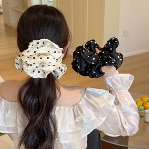 Dettaglio di elastici per capelli in raso oversize con pois classici e volant stratificati