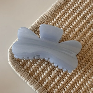 Detailed view of light blue glittery butterfly hair claw clip on woven texture