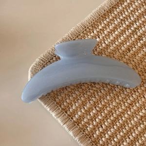 Detail showing high-gloss light blue resin hair claw clip with subtle glitter finish