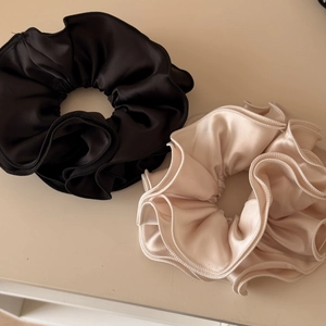 Vista dettagliata di elastici per capelli in raso nero e beige con bordi plissettati