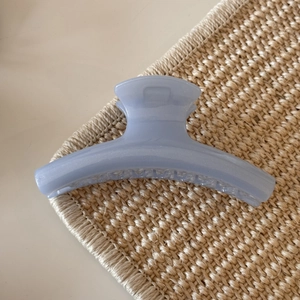 Macro detail of the light blue jelly hair claw clip with subtle pearlescent shimmer texture
