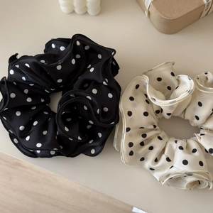 Dettaglio di elastici in raso a pois neri e bianchi accanto a una scatola regalo