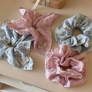 Detail of plaid oversized scrunchies with decorative buttons and woven labels