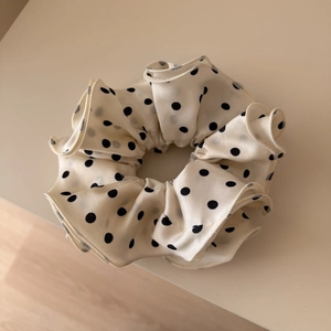 Dettaglio dell'elastico in raso premium con pois neri su tessuto color crema