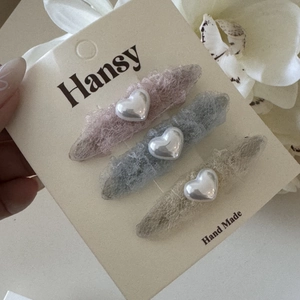 Détail de barrettes à cheveux en dentelle en forme de cœur avec perles en trois couleurs