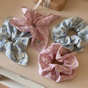 Detailed view of pink and blue plaid scrunchies with ribbons and decorative labels