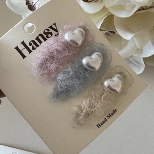 Détail de trois barrettes à cheveux en dentelle en forme de cœur sur carte Hansy