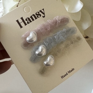 Détail de lot de 3 barrettes en dentelle avec cœurs argentés en rose, bleu et beige