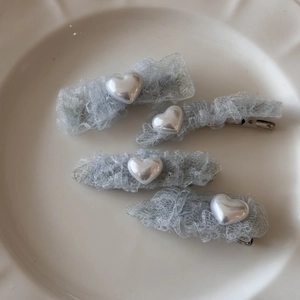 Détail d'un lot de 4 pinces à cheveux coeur en dentelle avec perles sur plateau céramique