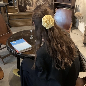 Elegante haarklem met gele geruite roos van stof, gestyled op het achterhoofd van een vrouw