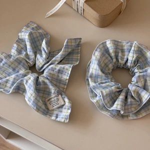 Detail of blue plaid bow scrunchie with button and Happy Smile label on gift box
