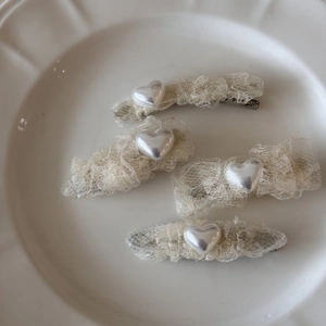 Détail de quatre barrettes en dentelle avec cœurs en perles sur un plateau en céramique