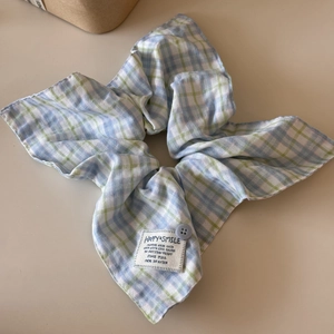 Detail of pink and blue plaid scrunchie with fabric label and decorative button