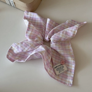 Detail shot of pink plaid scrunchie with soft fabric texture and decorative button